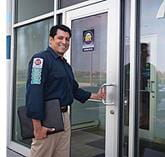 H V A C technician smiling and rabout to open the door to enter the office