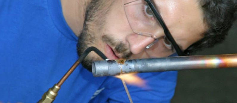 A Brownson graduate welding a pipe
